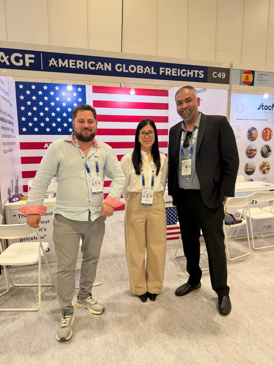 AGF team members with a visiting partner in front of the booth’s ocean freight display